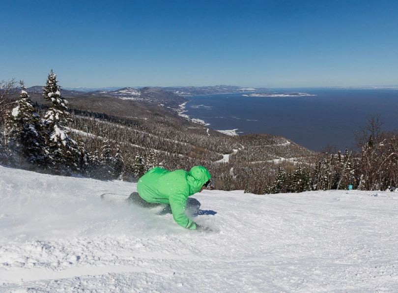 a snowboarder in green carves deep
