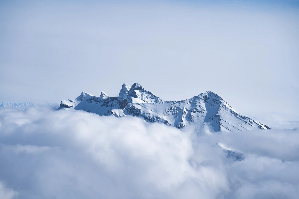 The peaks of a mountain massif poke through the clouds in a majestic picture