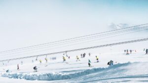 a t-bar and skiers dotted over a low-pitched glacier ski slope during a summer glacier ski session
