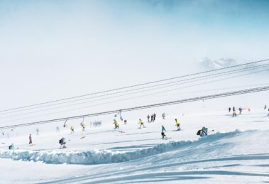 a t-bar and skiers dotted over a low-pitched glacier ski slope during a summer glacier ski session