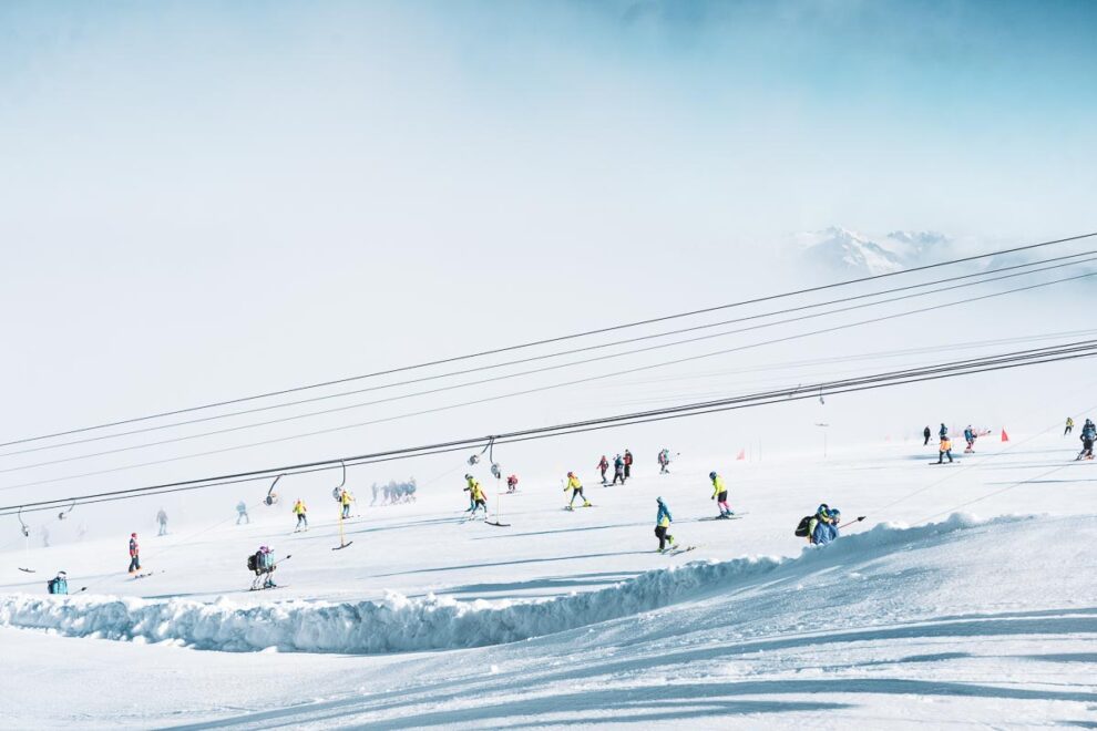 a t-bar and skiers dotted over a low-pitched glacier ski slope during a summer glacier ski session