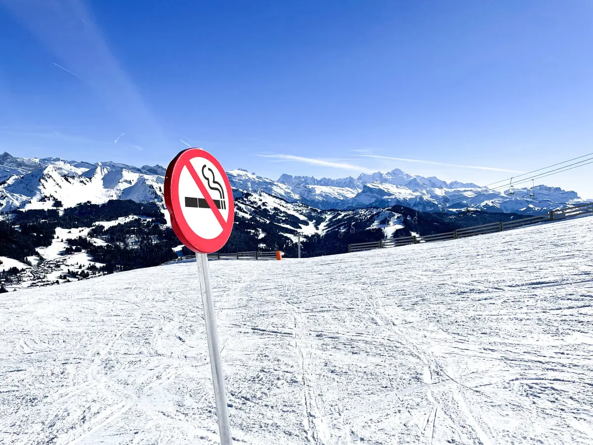 a no smoking sign on the edge of an empty ski slope