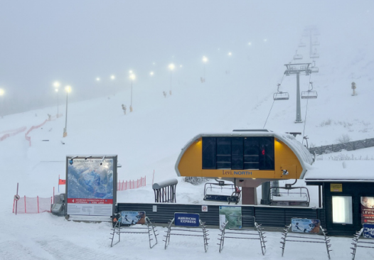 a chair lift station pictured in the snow, with empty ski racks