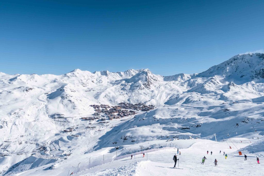 Val Thorens cradled in the high mountains, skiers on pistes in the near-ground