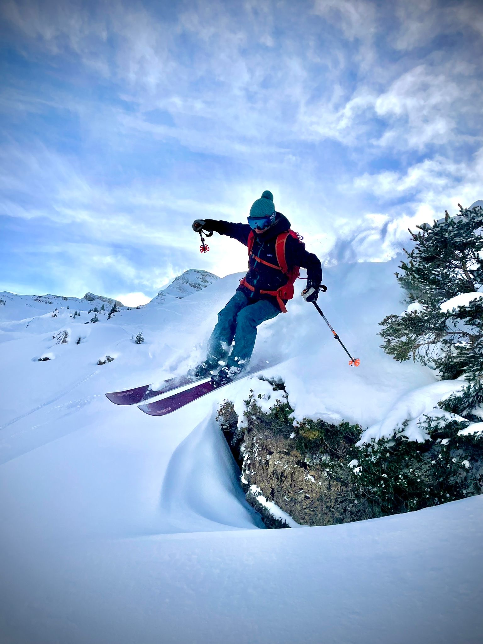 a skier taking a little air off a rock on fresh snow