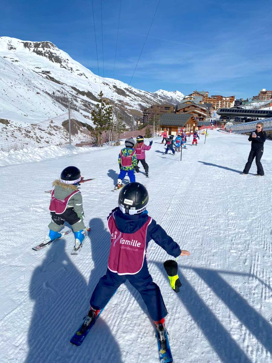 a line of ski school kids wearing ski famille vests