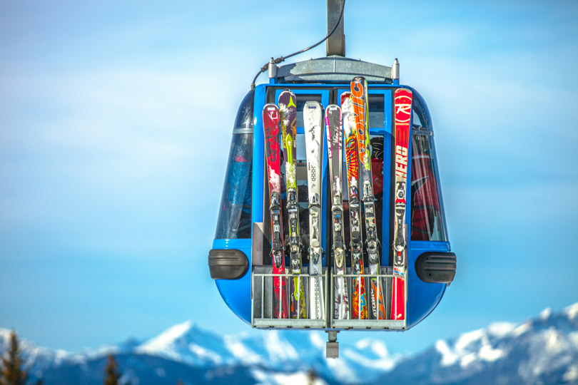 colourful skis loaded on a gondola in an ad for ski rental discount code