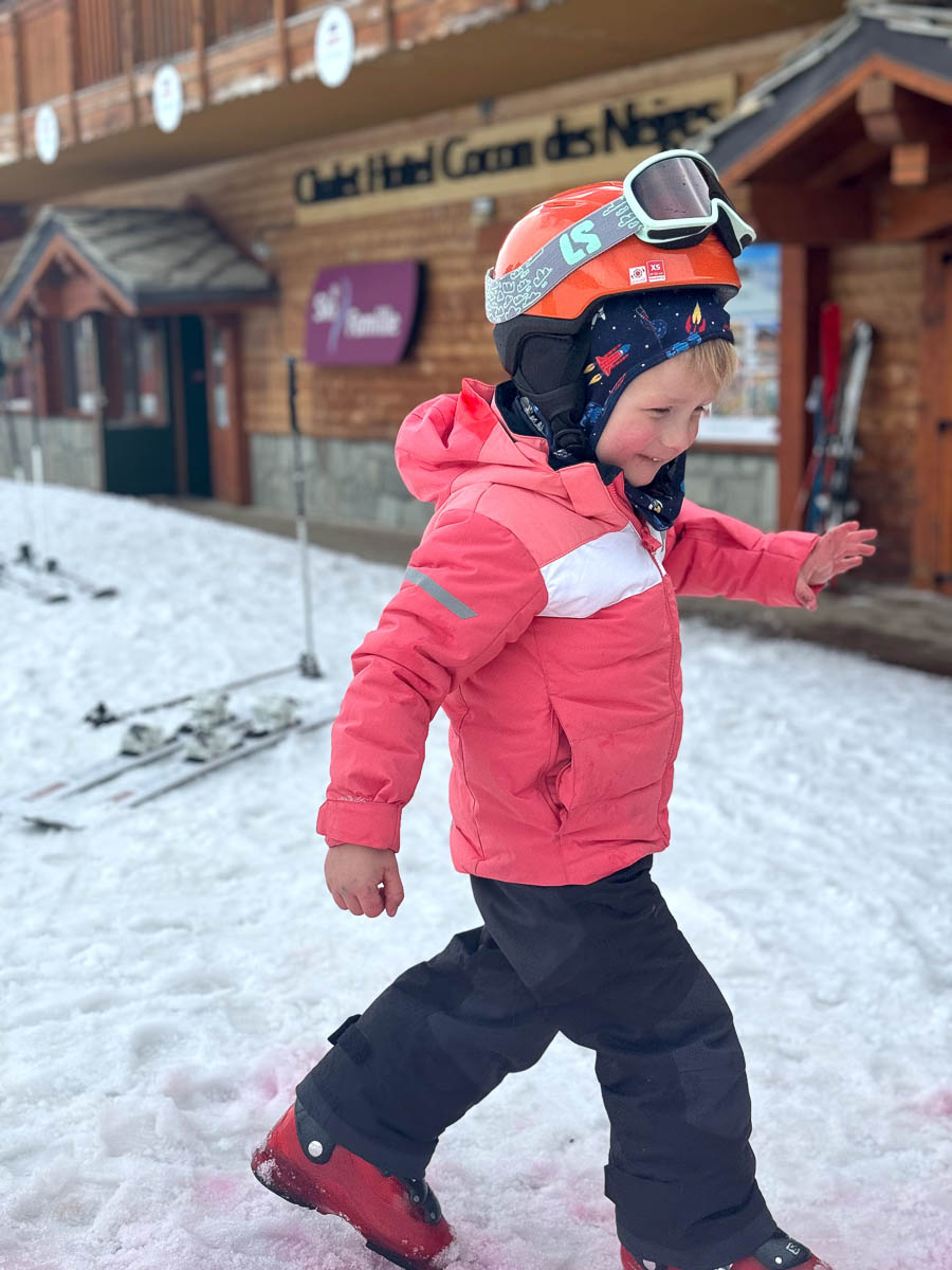 a happy young skier walking in ski boots outside hotel/chalet on a family ski holiday in the 3 Valleys