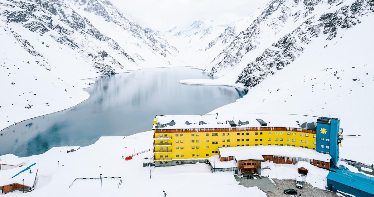 the iconic yellow hotel of Portillo ski resort in Chile, situated on the edge of a lake, pictured here on a cloudy snowy day