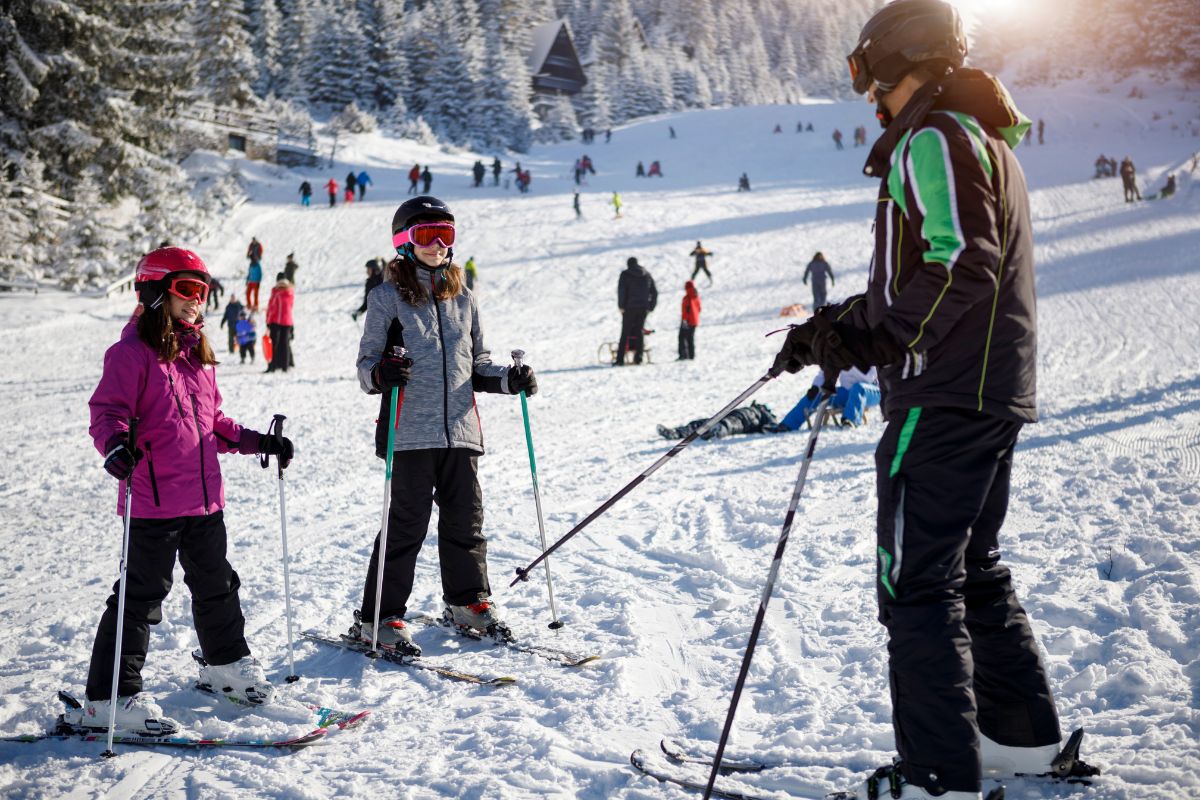 Ski instructor teaching two children on a beginner slope in a ski resort
