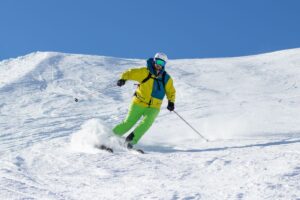 A skier executing a dynamic turn after improving their technique, with visible snow spray indicating control and confidence.