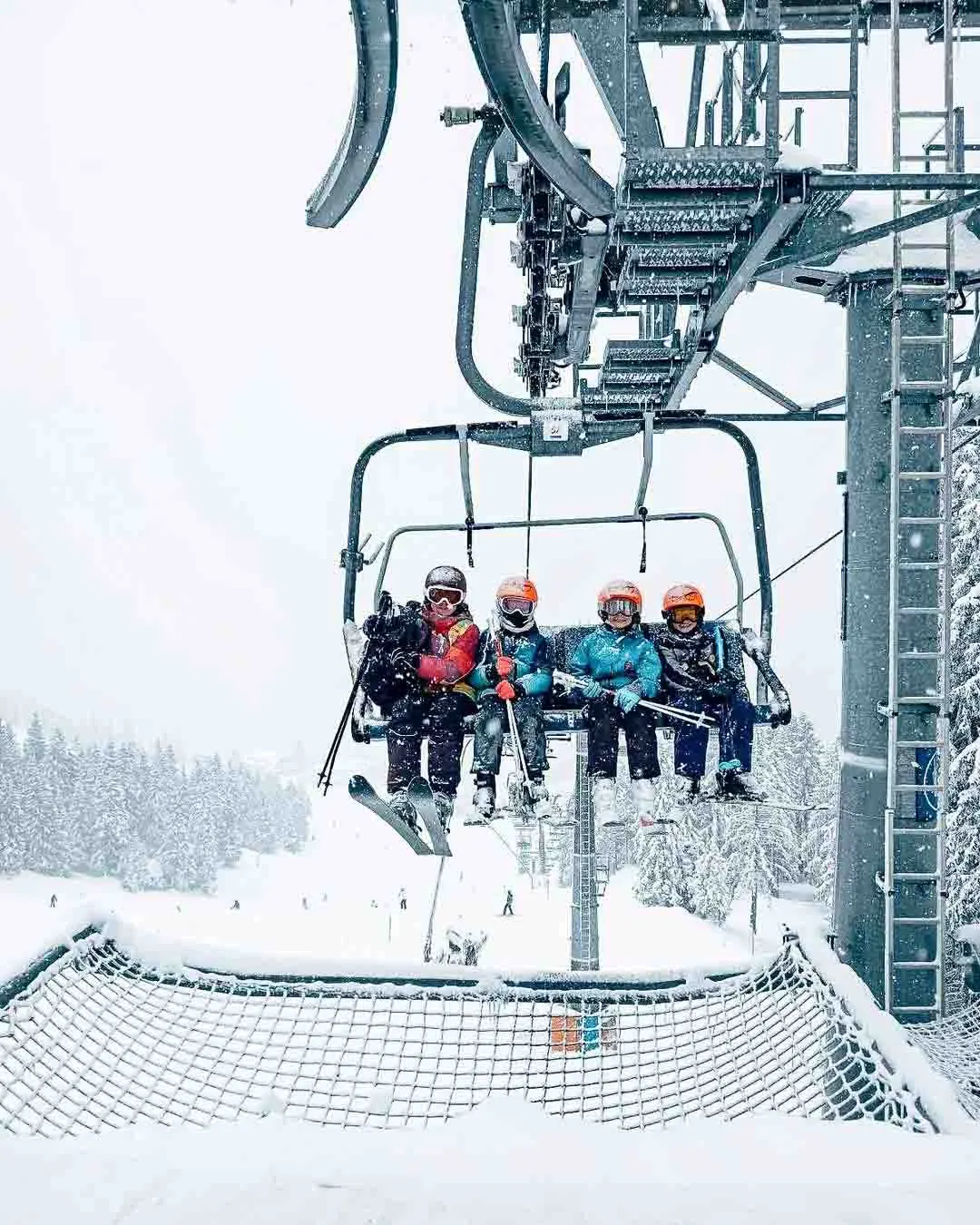 four smile as they get ready to offload a chairlift, in fresh snow