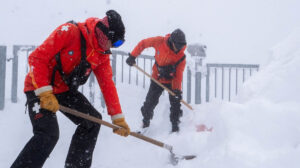 patrol guys digging fresh fallen snow in a whiteout