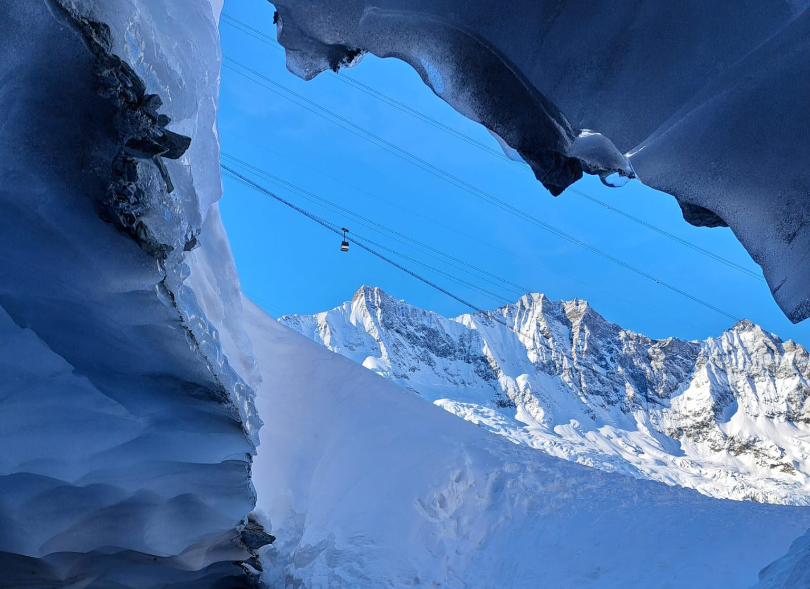 a photo of a distant cable car taken from inside the frame of a snow cave