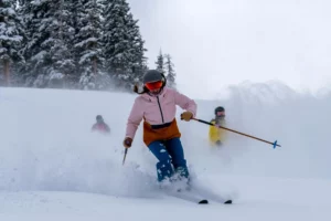 three skiers smile large, skiing towards camera through fresh light snow