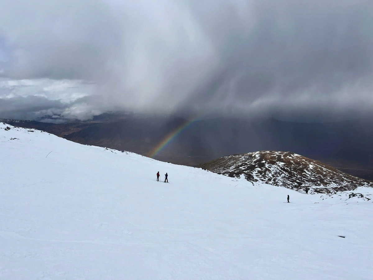 a rainbow is pictured between cloud and snow, high in a Scottish ski area
