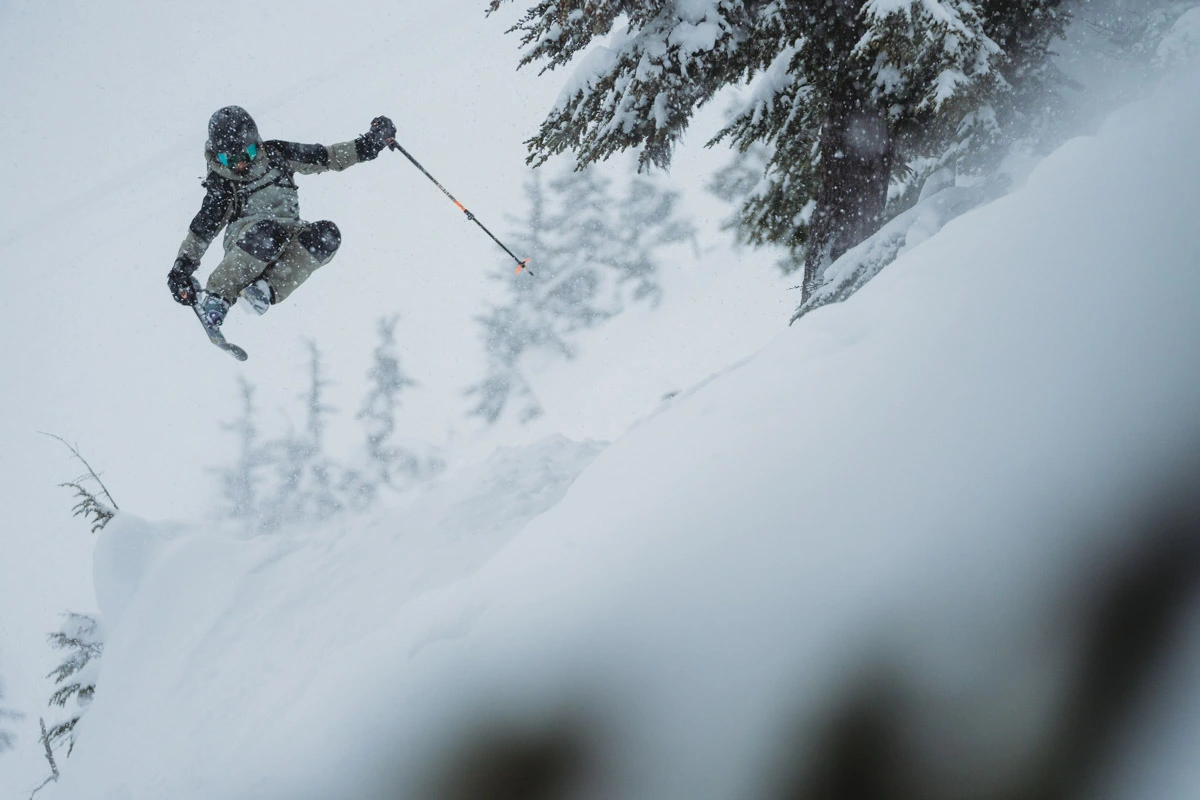 a skier grabs skis, in air, somewhere deep off piste in the trees