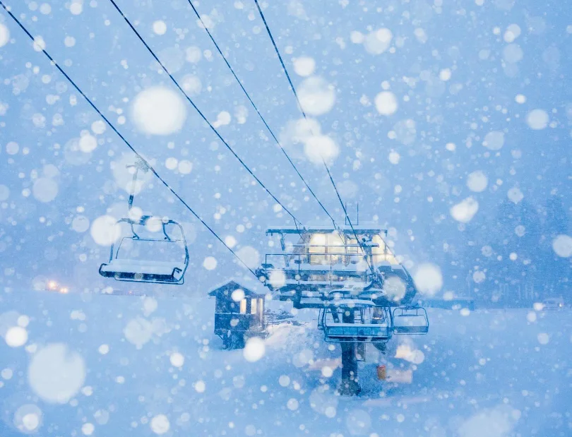 snowflakes dominate, a snowy chair.lift the background