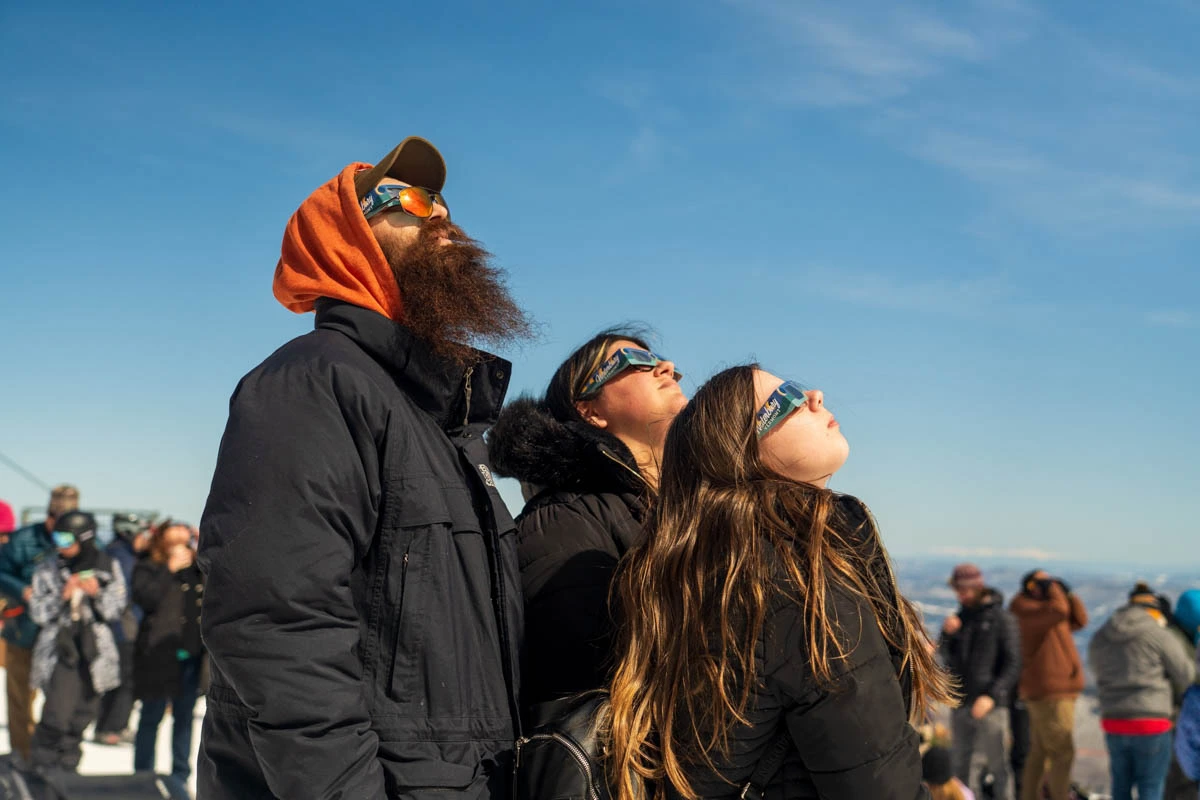 three look up at the eclipse wearing special glasses
