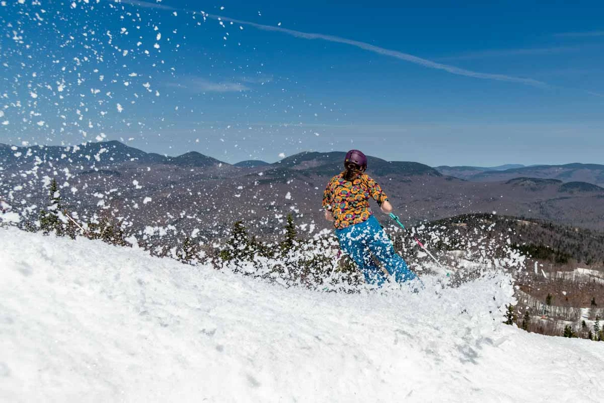 skier on spring snow, sprays the slush as they ski pas camera
