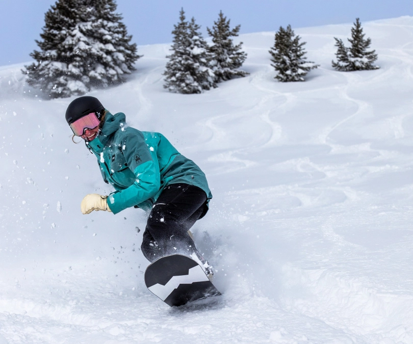 a snowboarder smiles, making fresh tracks on a mellow off-piste slope