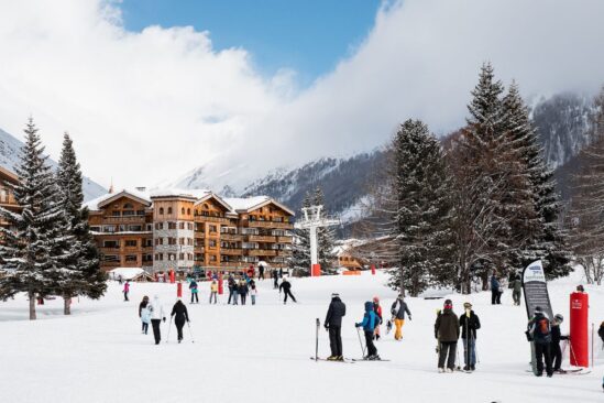 Skiers and families enjoying the base area with chalets and trees in Val d'Isère resort.