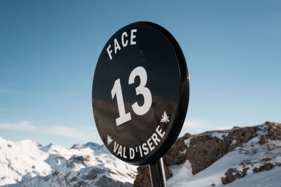 Sign marking the Face 13 ski run in Val d'Isère with snowy peaks in the background