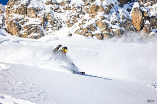 Skier enjoying a deep powder day on snowy slopes in Val d'Isère with mountains in the background.