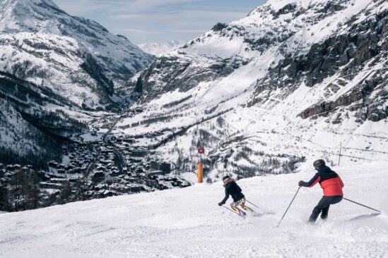 Skier carving down a steep snowy slope with majestic Val d'Isère mountains in the background