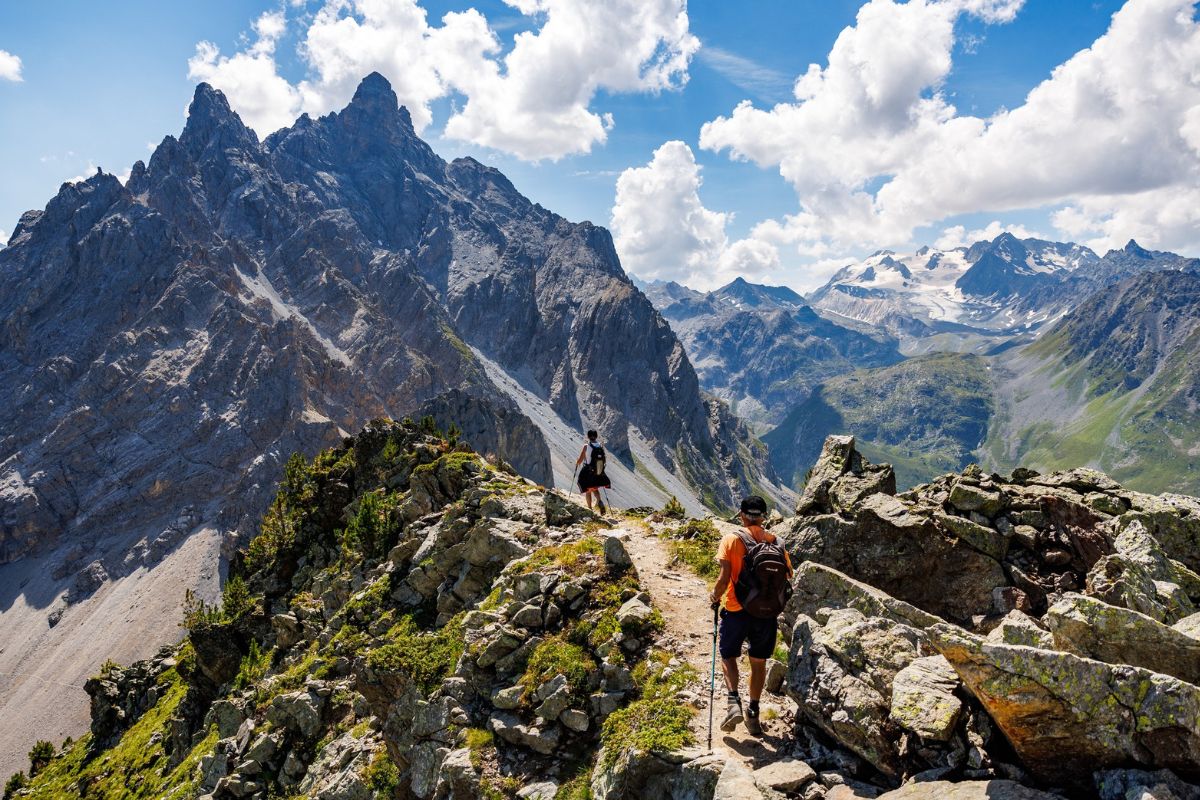 Hikers walking along a rocky alpine trail with panoramic views in Méribel